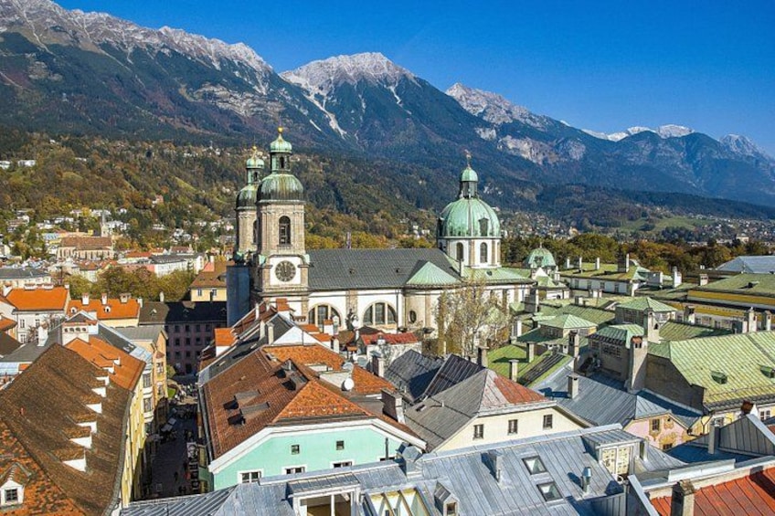 A town with a prominent church featuring two green domes, surrounded by mountains and red-roofed buildings. 5