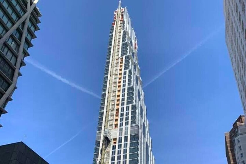 A tall skyscraper with a modern design, surrounded by other buildings. 3