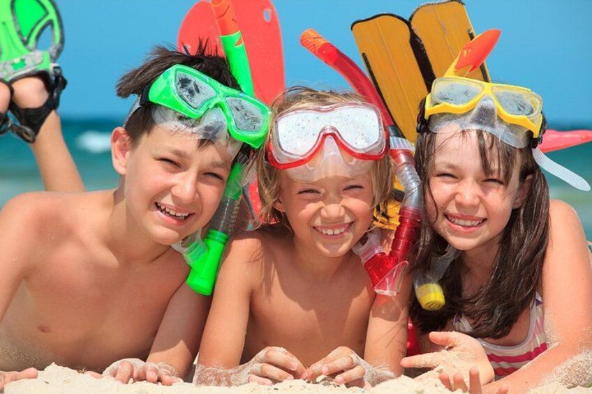 Three people on a sandy beach with snorkeling gear. 3