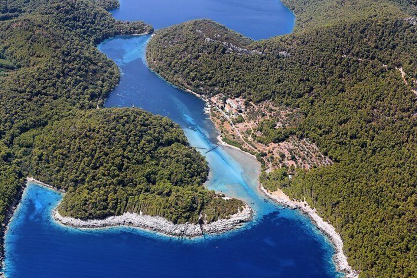 An aerial view of a coastal area with a winding river, surrounded by dense forests and a clear blue sea. 3