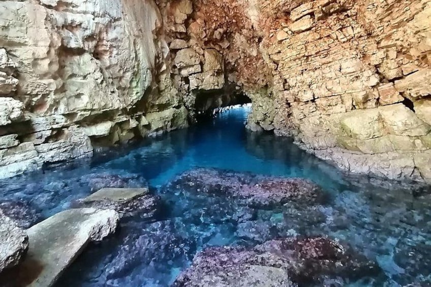 A natural cave with clear blue water and rocky formations. 2