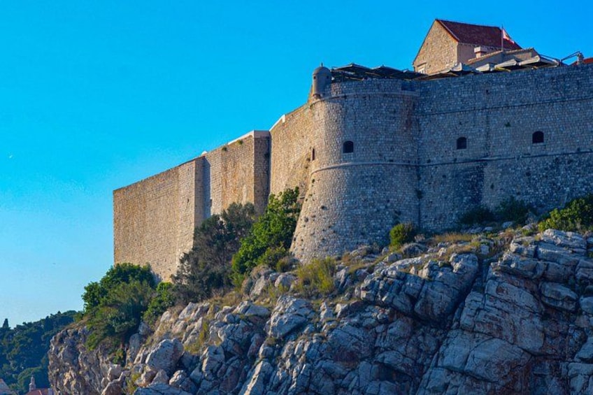 A historic stone fortress on a rocky hill with a clear blue sky. 3