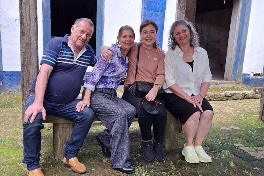 Four people sitting on a bench in front of a building with blue and white walls. 5