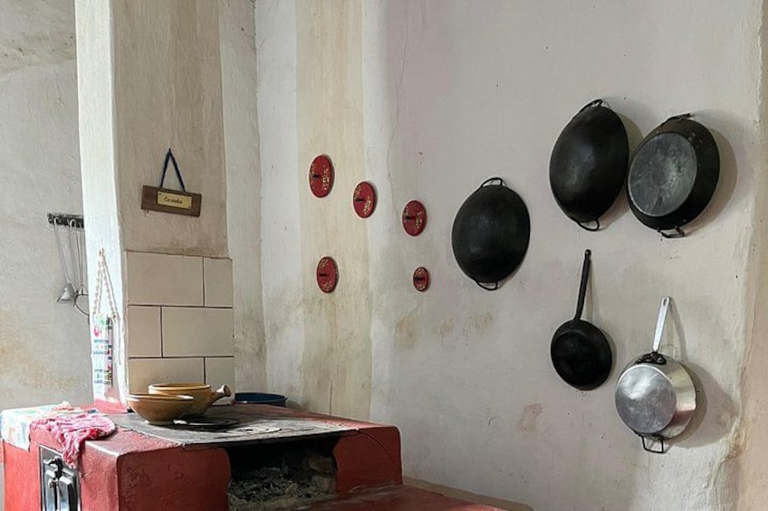 A kitchen with a red stove, hanging pots, and a tiled wall. 2