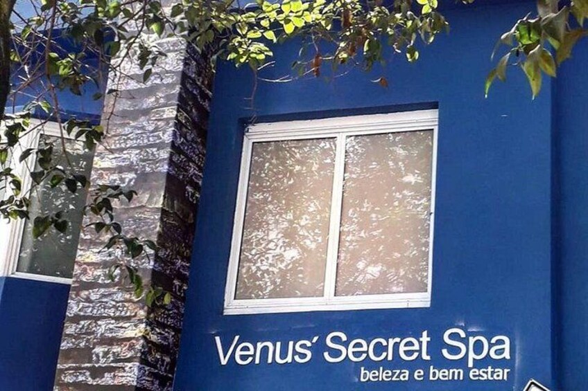 Fachada de edificio con un ventanal grande y el texto 'Venus' Secret Spa', junto con el eslogan 'beleza e bem estar'. 1