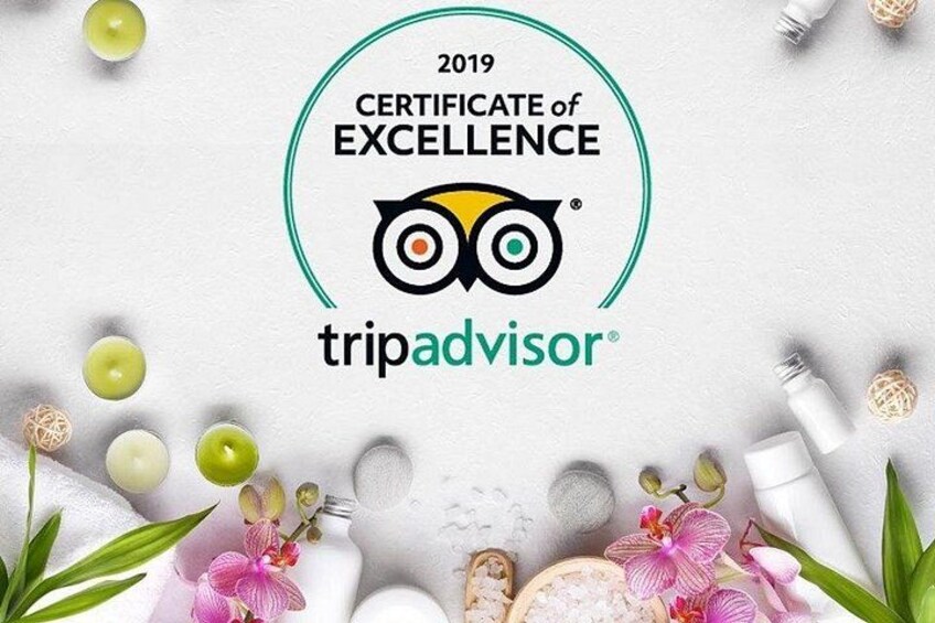 Certificado de Excelencia de TripAdvisor para 2019, rodeado de elementos relacionados con el spa, como velas, flores y productos de baño. 2