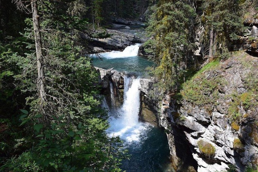 Una cascata che si getta da una rupe rocciosa, circondata da una fitta foresta. 4