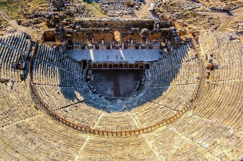 An ancient amphitheater with tiered seating and a central stage. 4