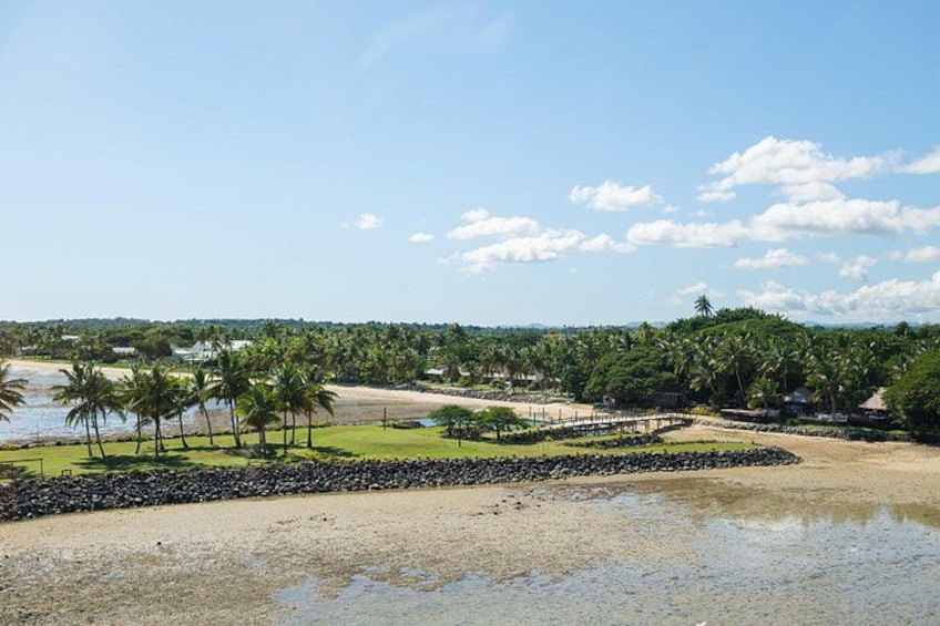 A beach with palm trees, a water body, and a distant shoreline. 2