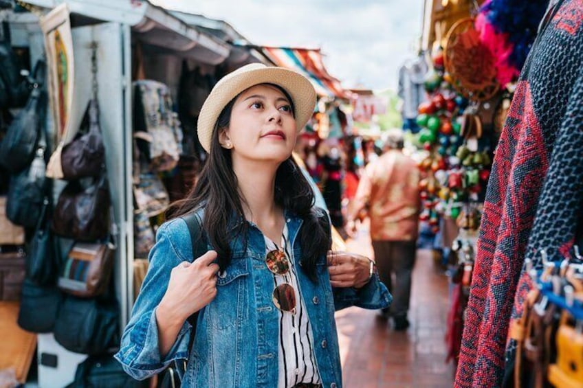A person in a denim jacket and straw hat at a market with various stalls. 4