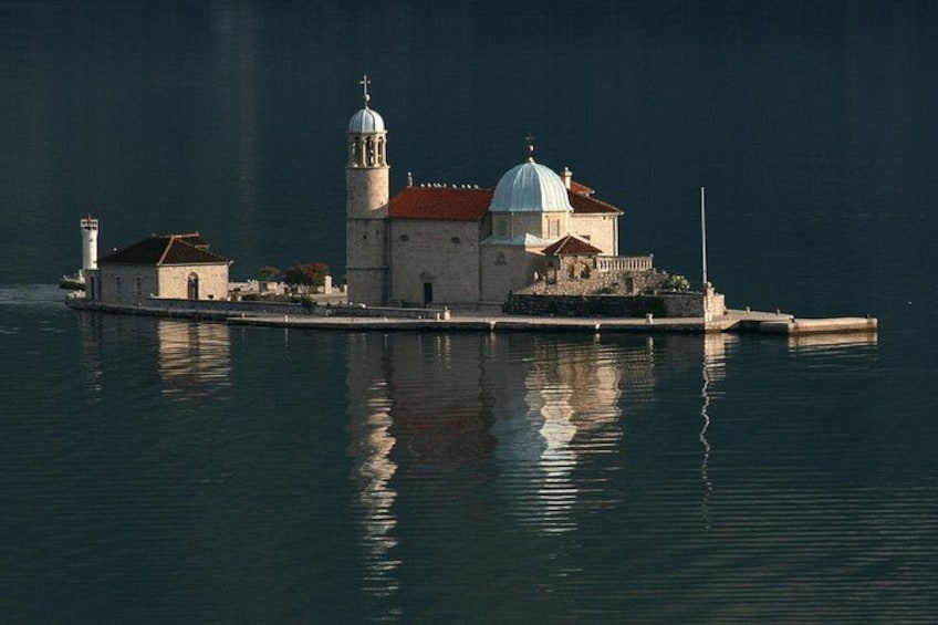 Eine Küstenkirche mit Glockenturm und Kuppel, umgeben von ruhigem Wasser. 4