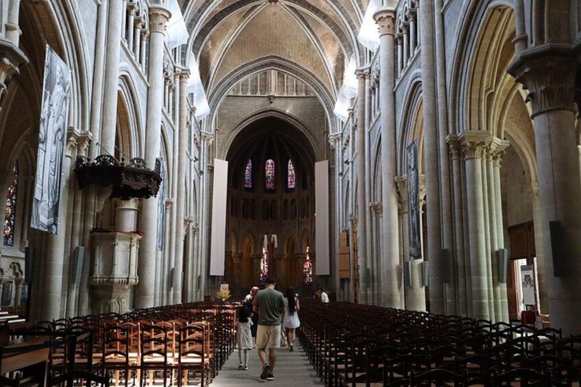 Interior de una catedral con altos techos abovedados, hileras de bancas y vidrieras. 4
