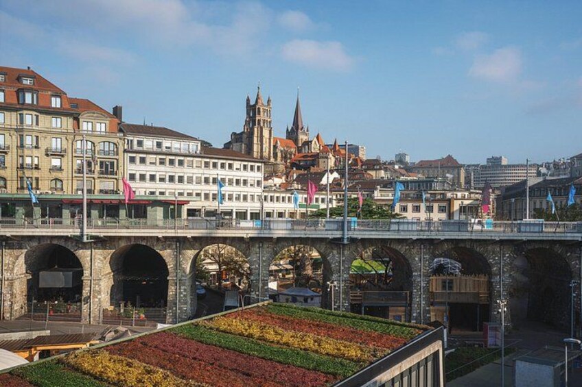 Een brug met bogen, een stadsgezicht met historische gebouwen en een bloementuin. 1