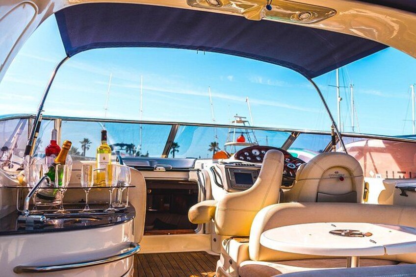 A boat's interior with a steering wheel, control panel, and seating area. 2
