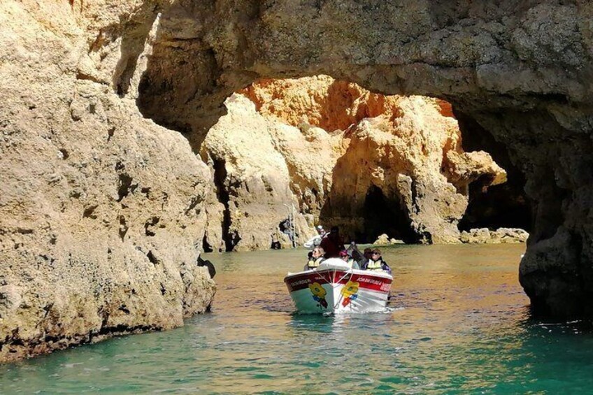 A boat with passengers navigating through a narrow waterway between rocky cliffs. 4