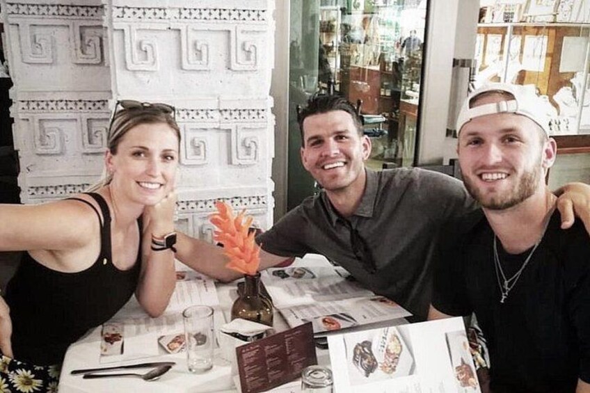 Three people seated at a table with a menu, a glass, and a decorative item. 2