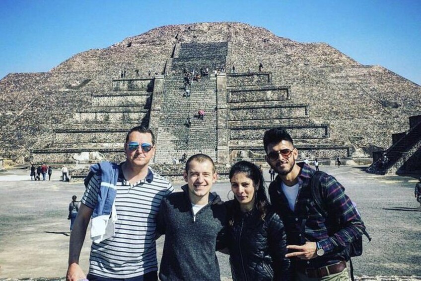 A group of people standing in front of a large pyramid-like structure. 3