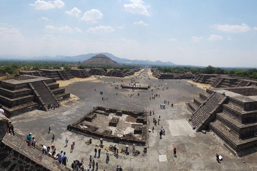 Een archeologische site met meerdere piramidevormige constructies en een groot open plein. 2