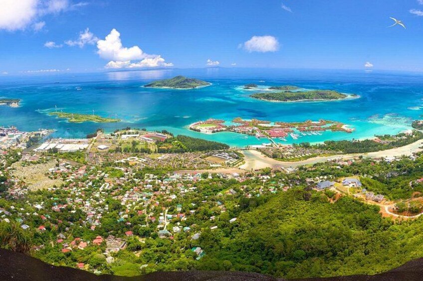 A coastal town with a beach, clear blue waters, and lush greenery. 5