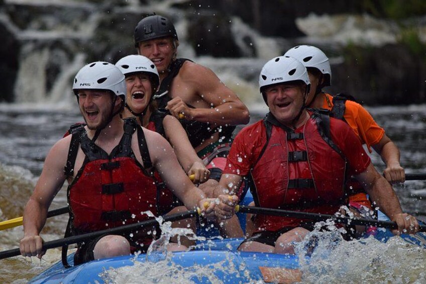 People in a raft navigating a river with rapids. 4