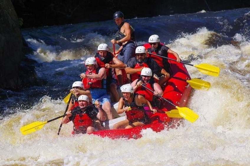 A group of people in a red raft navigating a river with rapids. 2