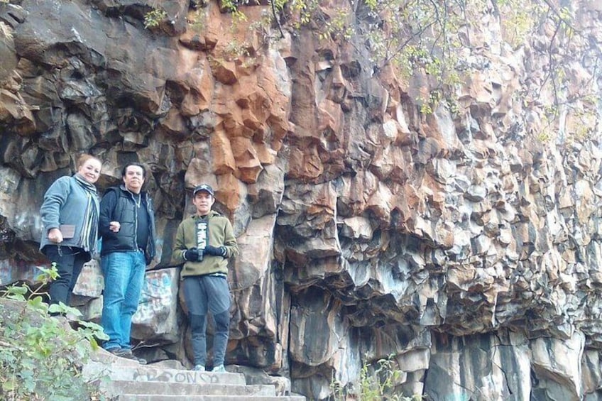 Three people standing on a rocky ledge with a rugged cliff in the background. 5