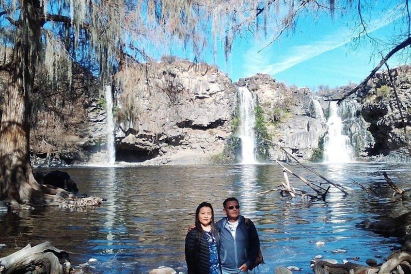 A waterfall, a couple, and a rocky landscape. 2