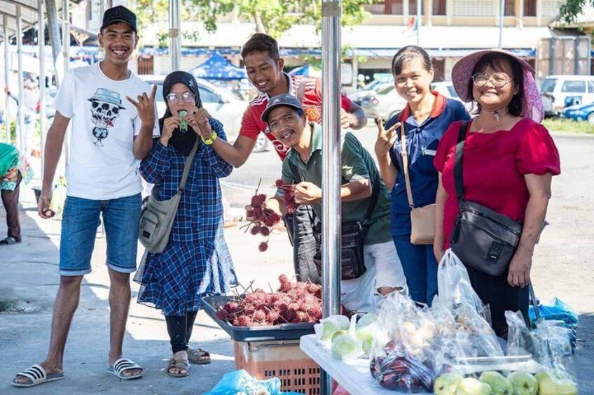 A group of people standing by a market stall with fresh produce. 5