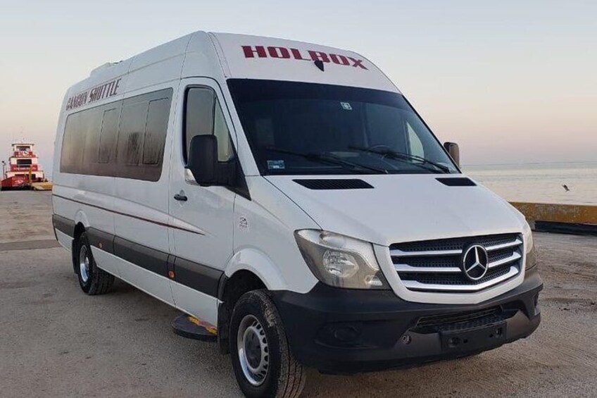 A white Mercedes van with 'HOT PAX' written on the front, parked on a beach with the ocean in the background. 3