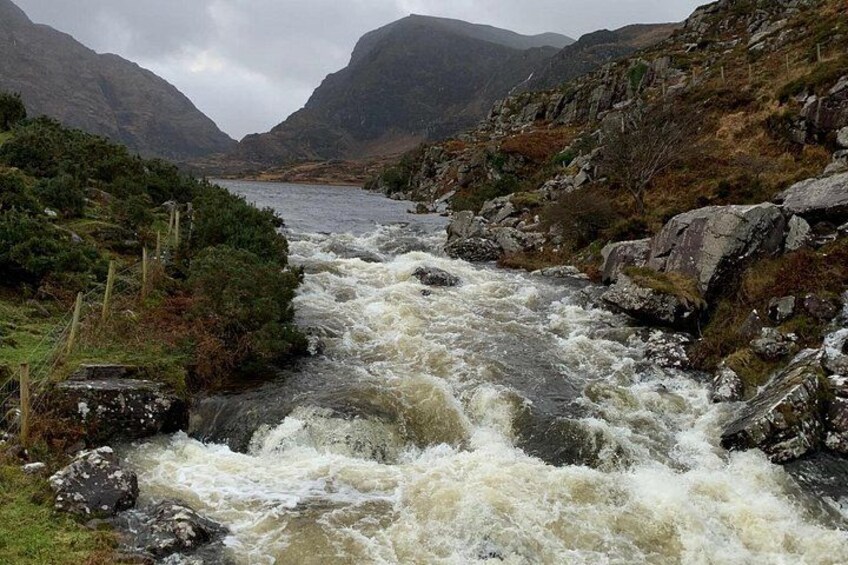 Un río turbulento que atraviesa un paisaje montañoso con orillas rocosas y una masa de agua distante. 4