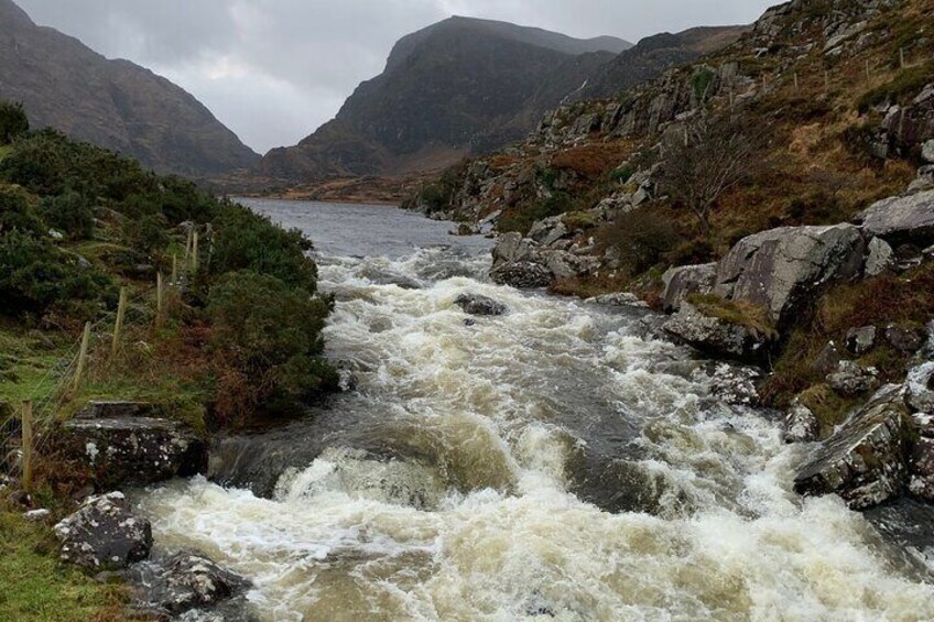 A turbulent river flowing through a rocky valley with mountains in the background. 4