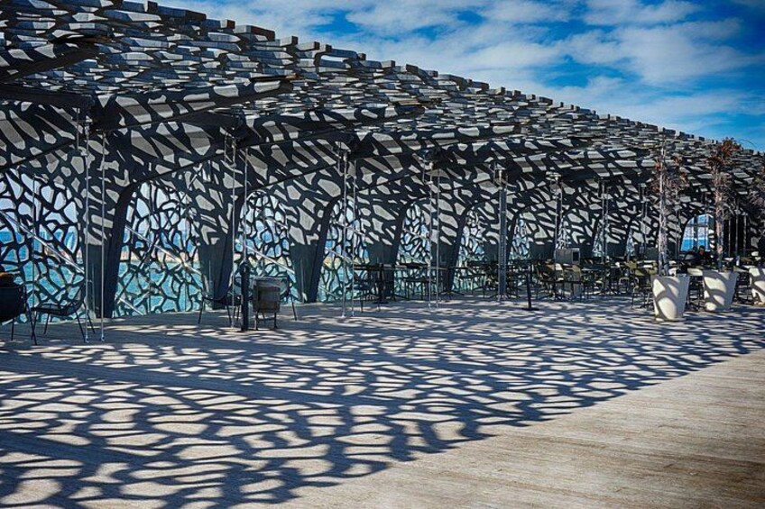Una estructura arquitectónica moderna con un diseño geométrico, un área pavimentada y cielo despejado. 3