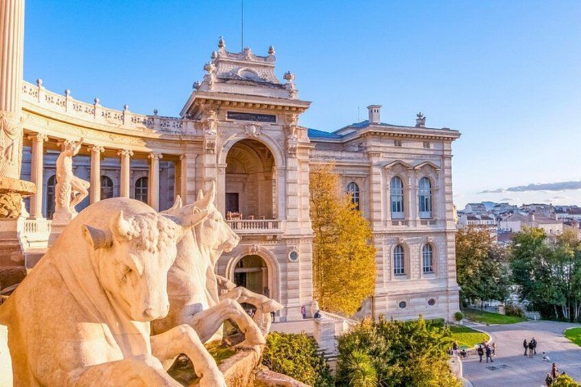 Un edificio histórico con arquitectura ornamentada, que incluye un arco central y estatuas de caballos. 2