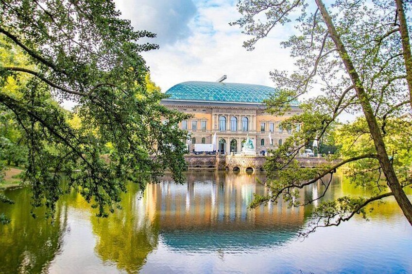 A historic building with a dome, reflecting in a calm body of water, surrounded by trees. 2