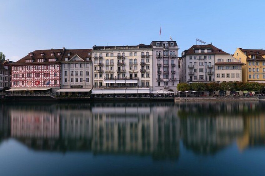 Une rivière paisible où se reflètent des immeubles dotés de balcons, sous un ciel dégagé. 3
