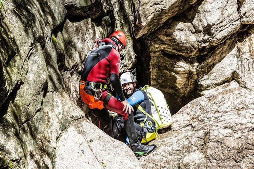 Two people in climbing gear sitting on a rocky ledge. 4