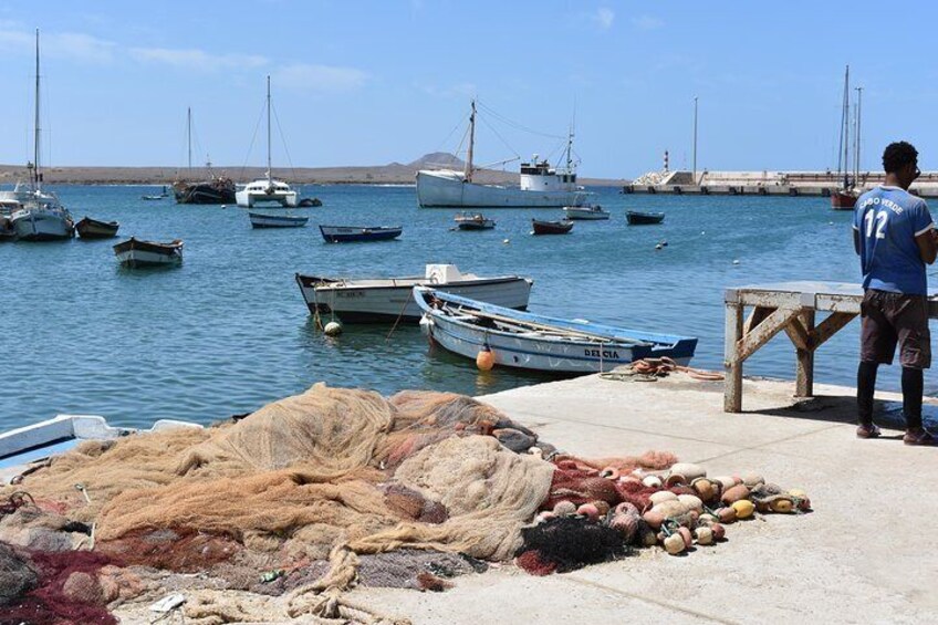 A harbor with boats, fishing nets, and a person standing by a table. 5
