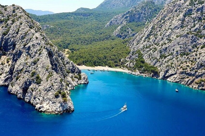 A coastal landscape with rocky cliffs, clear blue sea, and a boat in the water. 1