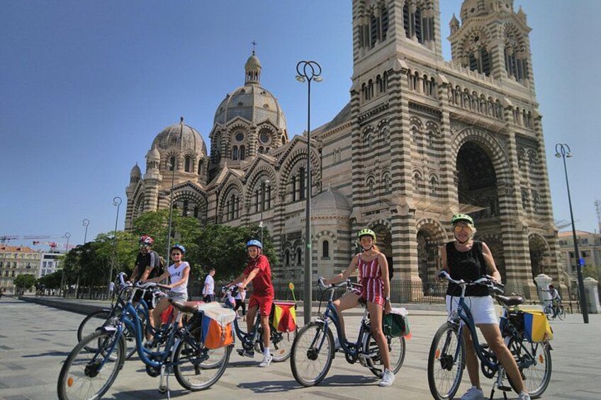 En gruppe mennesker på cykler foran en stor, udsmykket bygning med kupler og tårne. 4