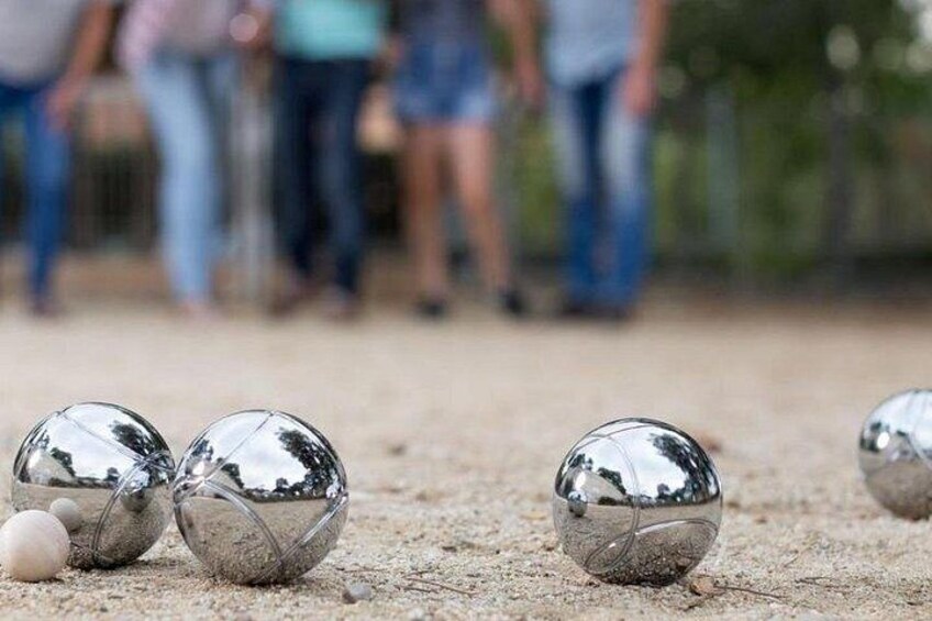 A beach setting with two shiny, reflective balls on the sand, and a few people in the background. 1