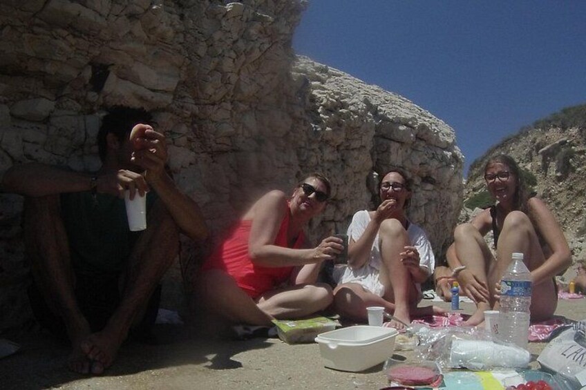 A group of people sitting at a table outdoors with a stone wall in the background. 3