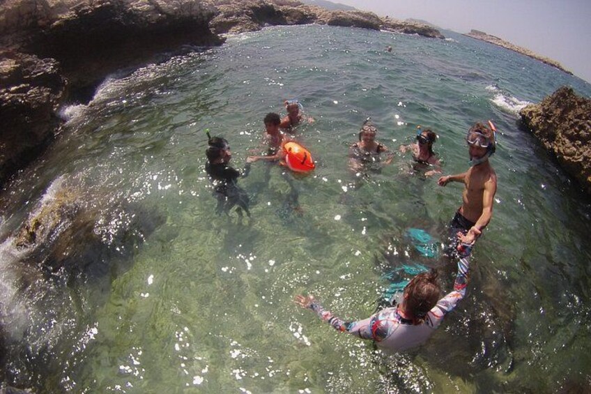 A group of people swimming in a clear, rocky coastal area. 2