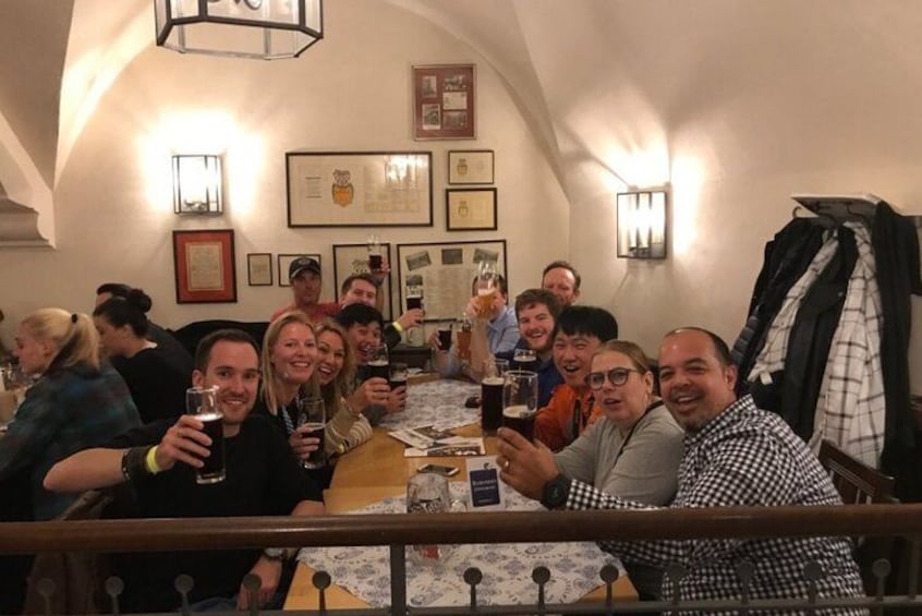 A group of people sitting around a table in a restaurant with framed pictures on the wall. 2