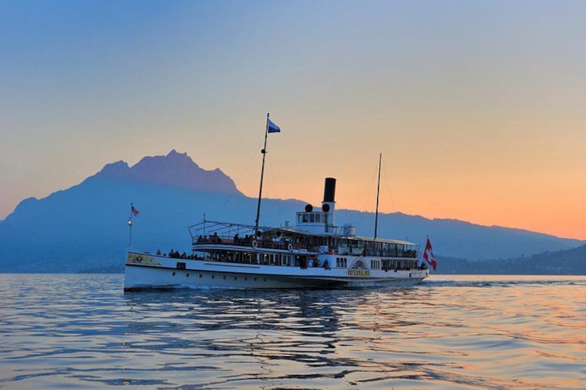 Un barco de recreo con banderas, un telón de fondo montañoso y aguas tranquilas. 3