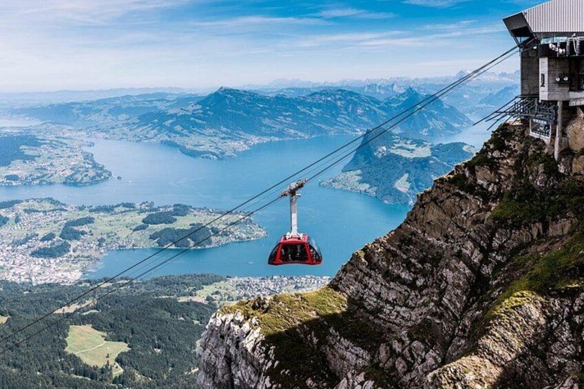 A cable car suspended over a mountainous landscape with a lake below. 1