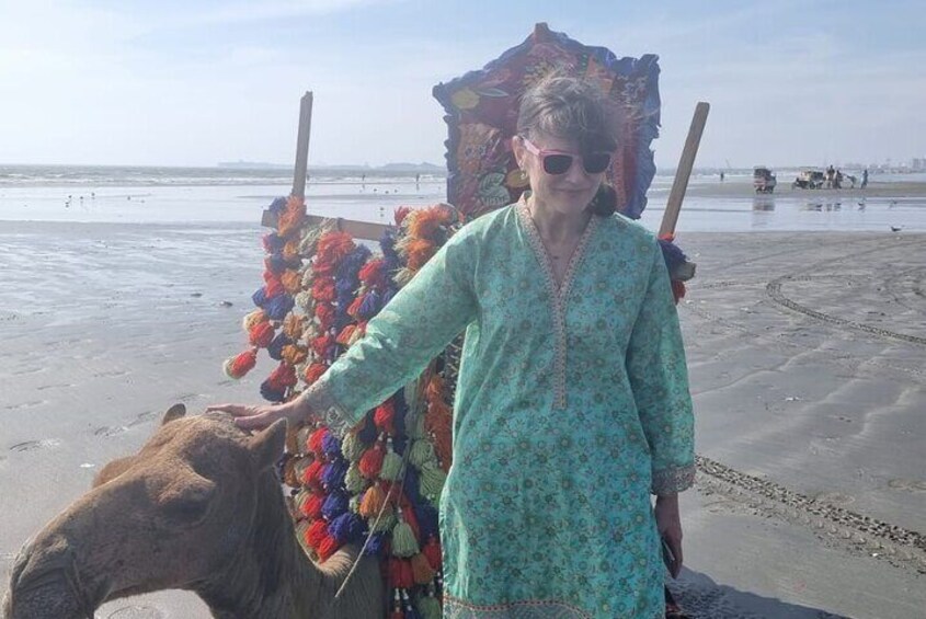 A person standing on a beach with a camel. 4
