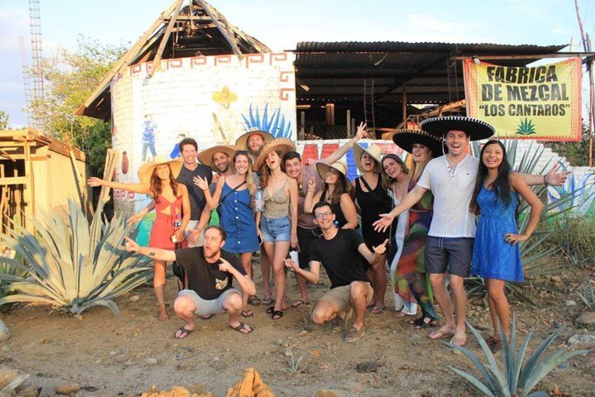 A group of people posing in front of a building with a sign that reads 'FABRICA DE MEZCAL LOS CANTAROS'. 4