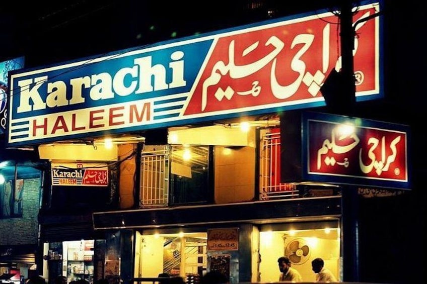A building with a sign that reads 'Karachi Haleem' and another sign with Urdu text. 1