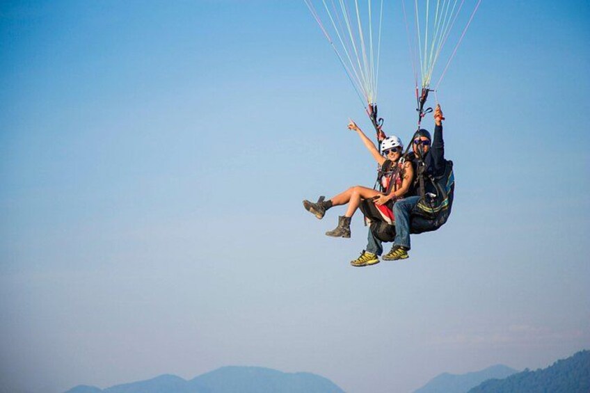 Two people paragliding with a clear sky and distant mountains. 2