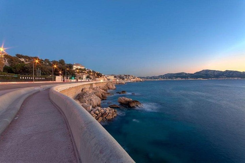 A coastal road with a curving path, rocky coastline, and distant mountains. 4